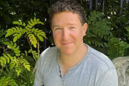 ADR voice casting director Jason Harris surrounded by plants outside.