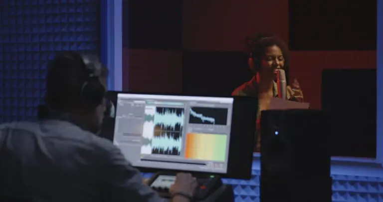 female voice actor revording in a studio as the sound engineer records on his computer.