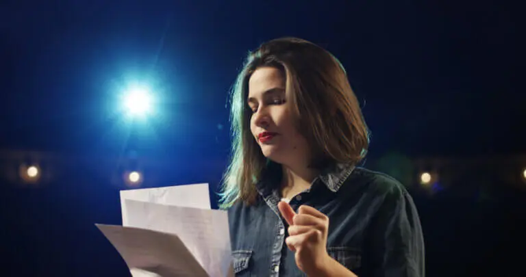 An actor in a denim jacket delivering a monologue onstage.