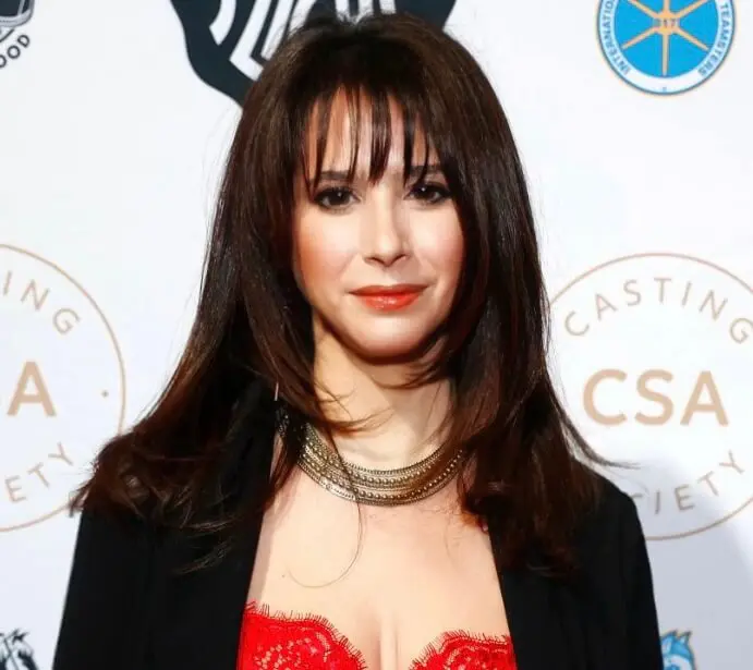 Casting director Allison Estrin smiling in a jacket and red dress at a show.
