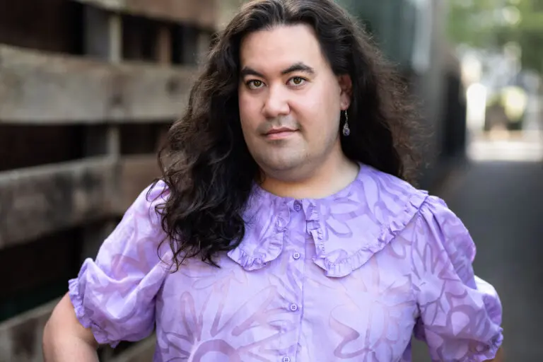 Casting Director Rhys Velasquez outside in a purple shirt.
