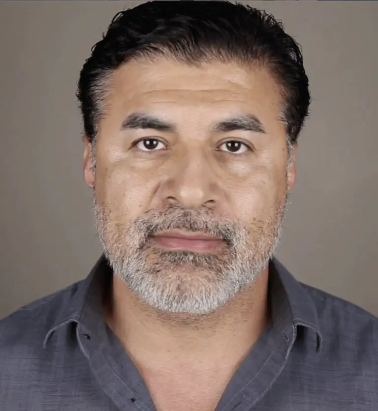 Gerardo Davila smiling in front of a grey background.