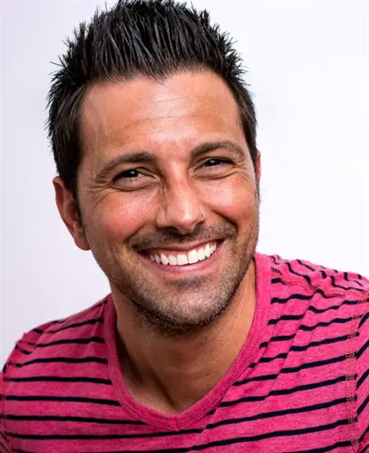Owen Markus smiling in front of a gray background.