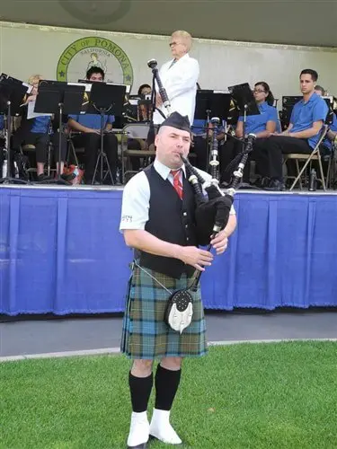 Orion McCabe in uniform on a field playing the bagpipes.