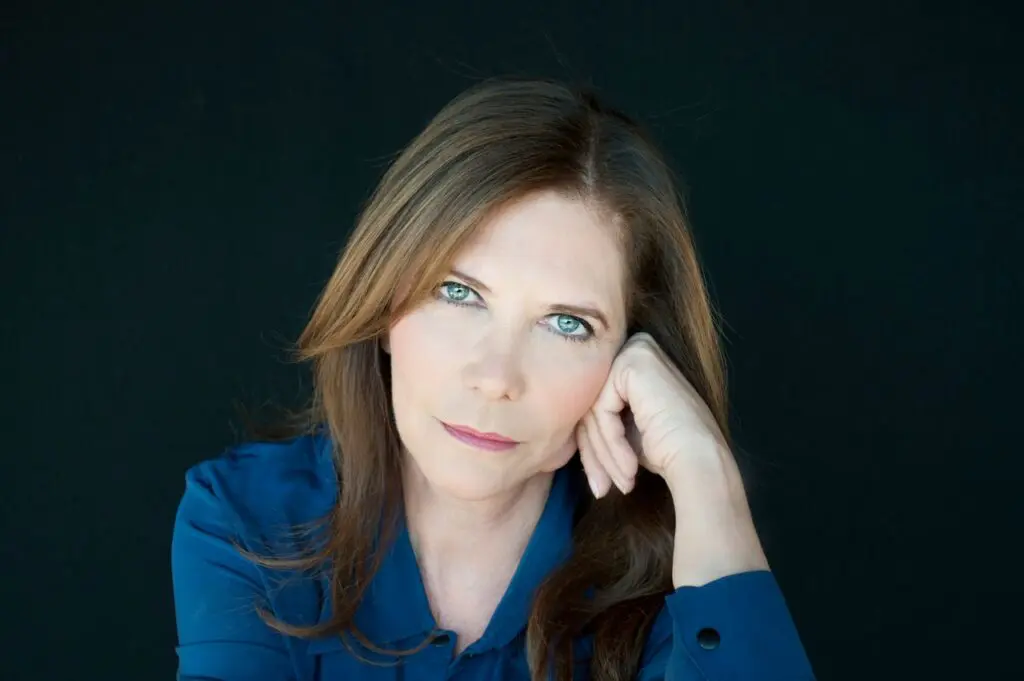 Acting teacher Ivana Chubbuck in a blue shirt smiling, hand folded and resting on her cheek.