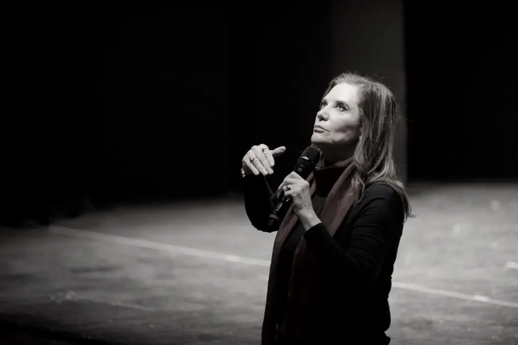 Acting teacher Ivana Chubbuck standing on a stage looking up. A black-and-white filter is applied.