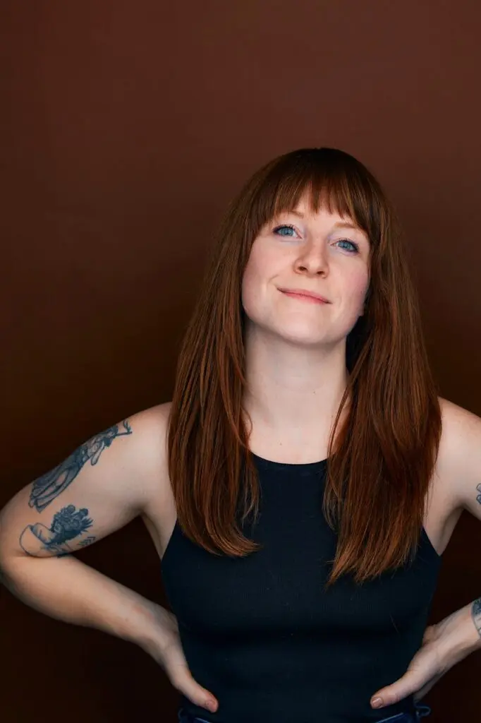Casting Director Sarah Cayce smiling and looking confident in front of an auburn backdrop.
