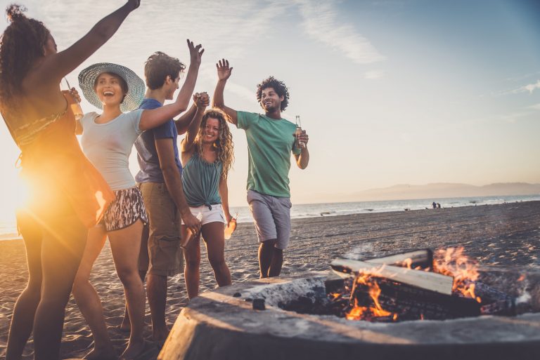 Multicultural group of friends partying on the beach - Young people celebrating during summer vacation, summertime and holidays concepts