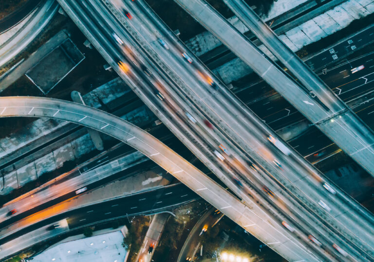 Aerial view of city landscape with autobahn motorway in metropolis, Bird's eye evening view. automobiles moving at street with modern automotive expressway. interchange road highway, junctions freeway