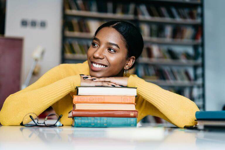 An actress with a pile of books about writing an acting cover letter.