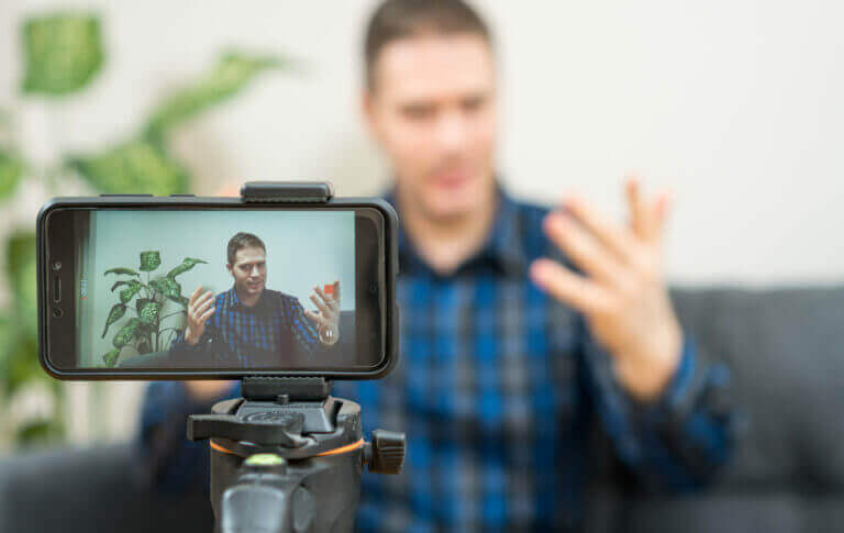 Handsome man making video blog. Focus on smartphone.