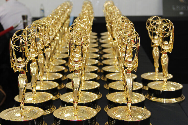 Emmy awards lined up on a black table waiting to be presented.