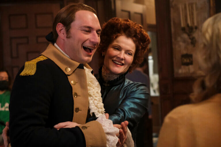 Actors Rebecca Wisocky and Brandon Scott Jones in 1700s soldier attire and a blue victorian dress on CBS' 'Ghosts.'