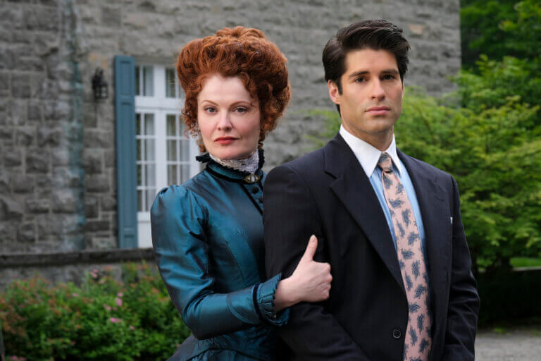 Actors Rebecca Wisocky and Asher Grodman in a Victorian dress and business suit in a garden for CBS' Ghosts.