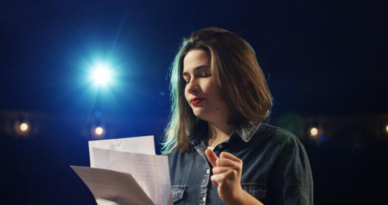 An actor in a denim jacket delivering a monologue onstage.