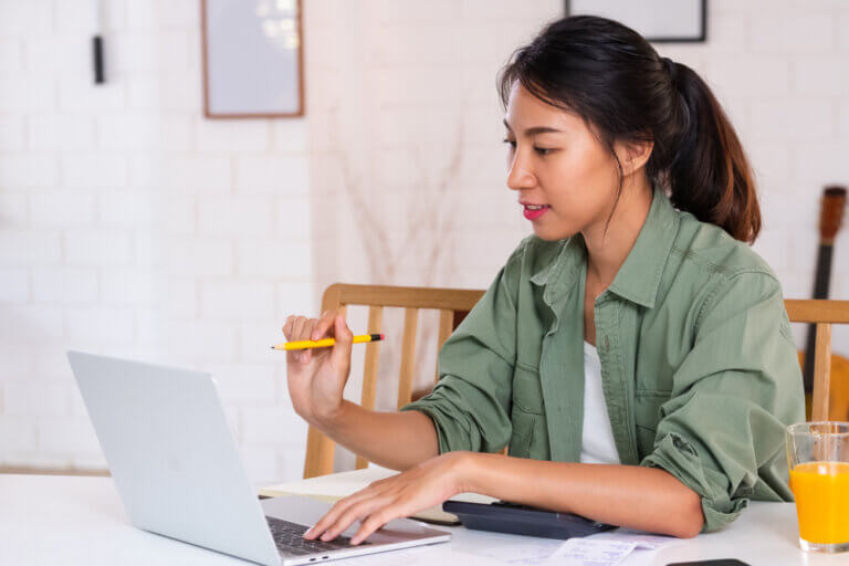 An actress on her laptop at the kitchen table doing her taxes.