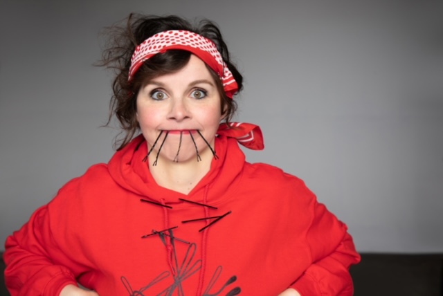 Audrey Moore wearing a red hoodie while trying to smile with bobby pins in her mouth.