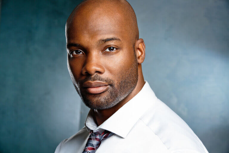 Actor Hiram A. Murray wearing a white shirt and tie.