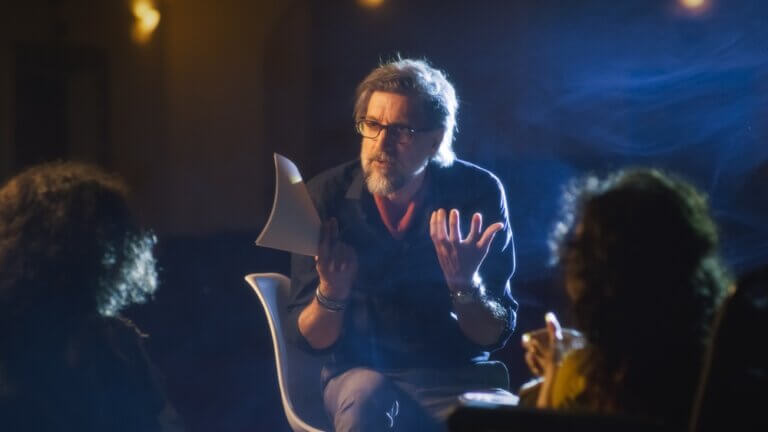 Two actors at rehearsal receiving feedback from their bearded director.