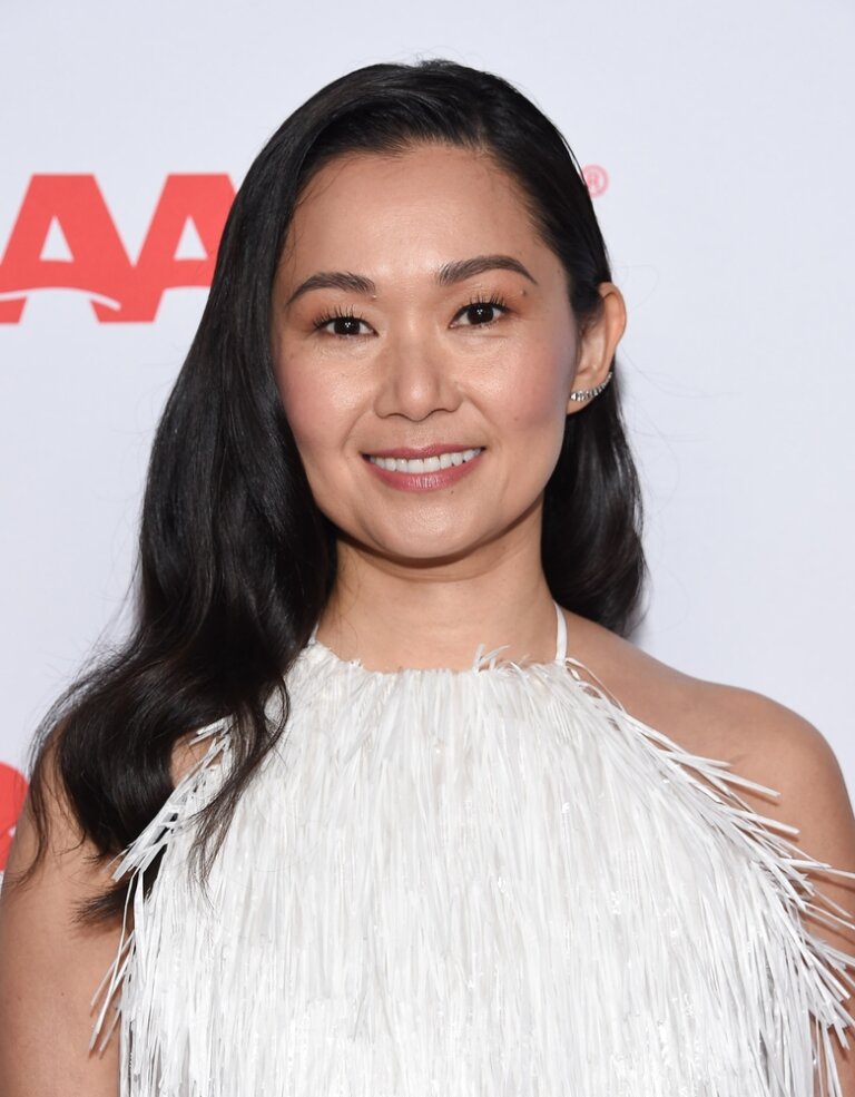 Actor Hong Chau smiling for a photo op while attending a movie event wearing a white dress.
