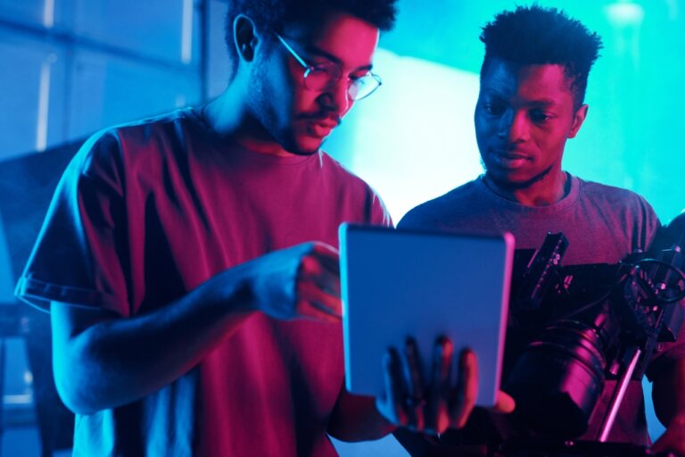 Two men talking, holding tablet on movie set.