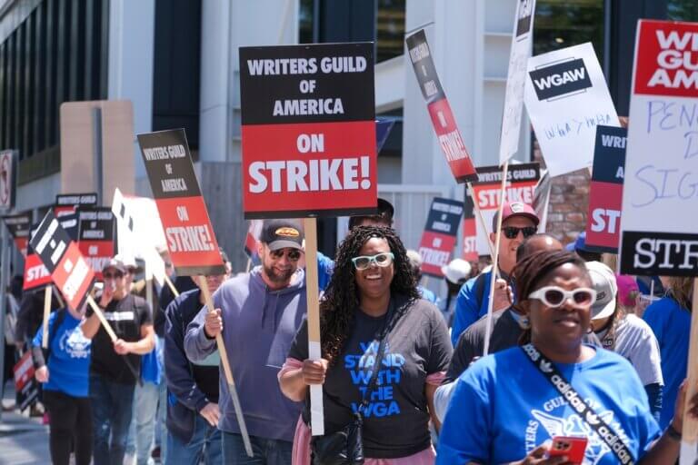 WGA writers on strike with picket signs in hand.