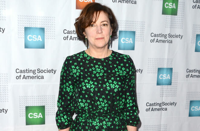 Casting Director Nina Gold wearing a green and black dress in front of a Casting Society of America backdrop.