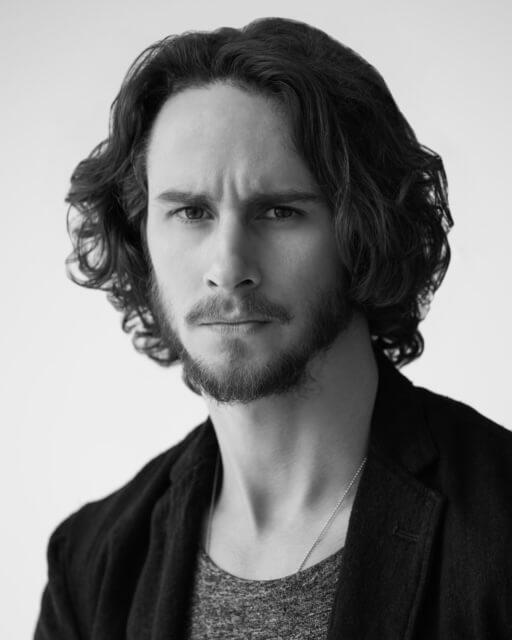 Black and white photo of actor Kelly Blatz in a t-shirt and blazer.