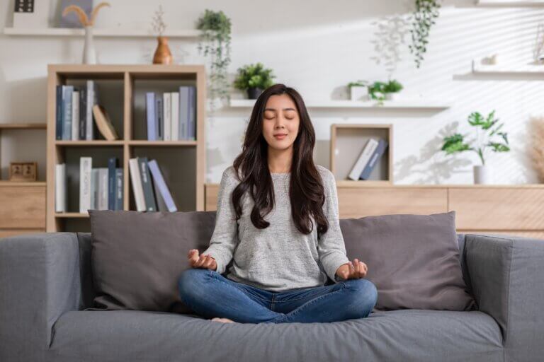Young Asian woman meditating on the couch.