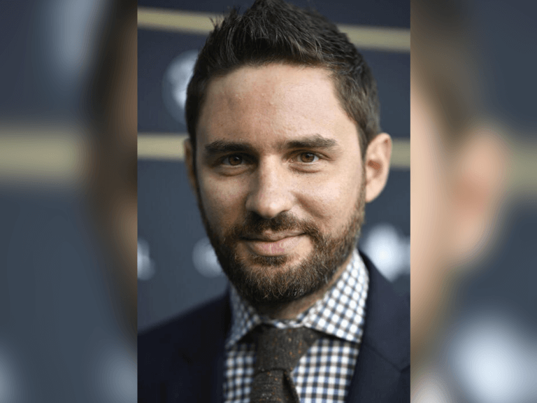 Film director Jared Moshé. looking at the camera smiling in a suit.