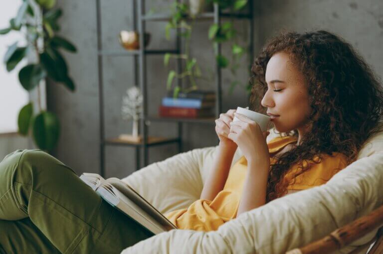 An actor relaxing inside her home drinking tea with a book in her lap after a long day on set.