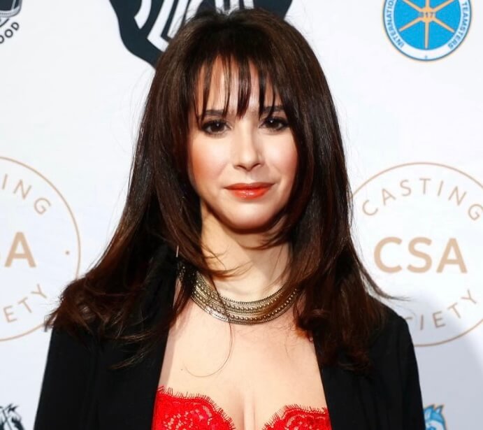 Casting director Allison Estrin smiling in a jacket and red dress at a show.