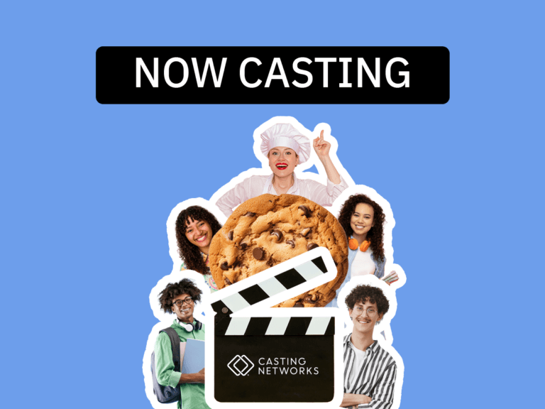 A giant cookie in the center of actors dressed as a baker, as well as actors in casual clothing smiling.