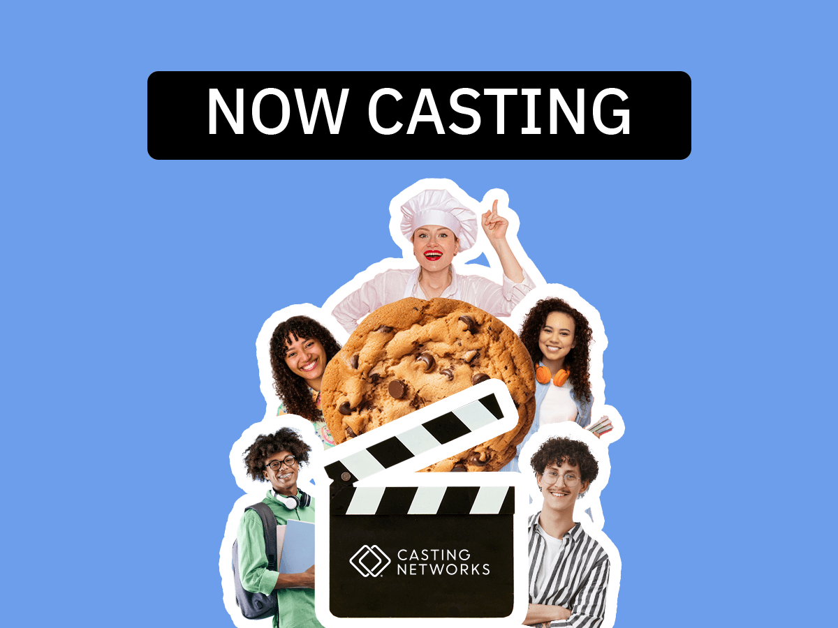 A giant cookie in the center of actors dressed as a baker, as well as actors in casual clothing smiling.