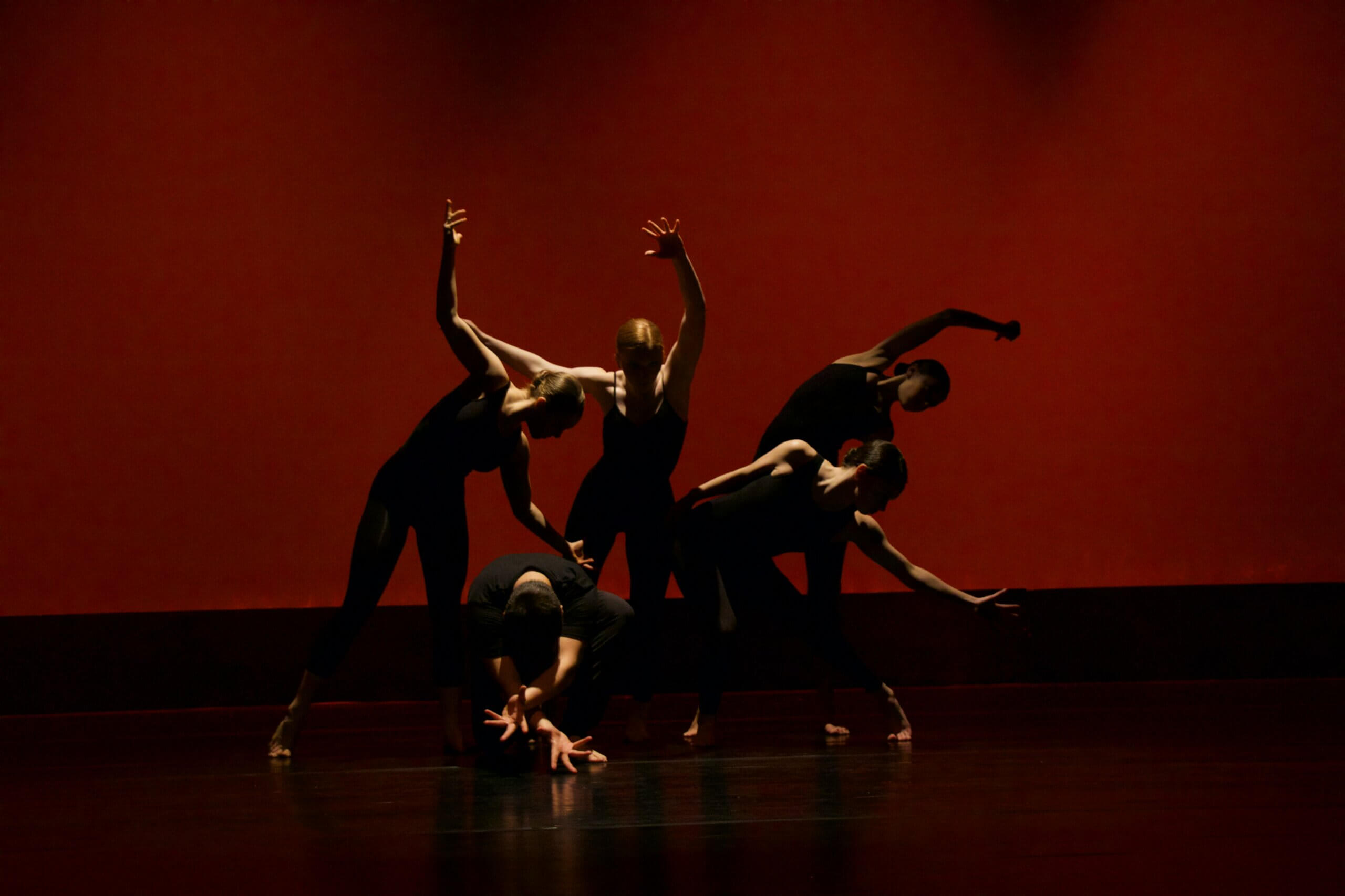 A group of actors on stage showcasing heavy emotion in movement.