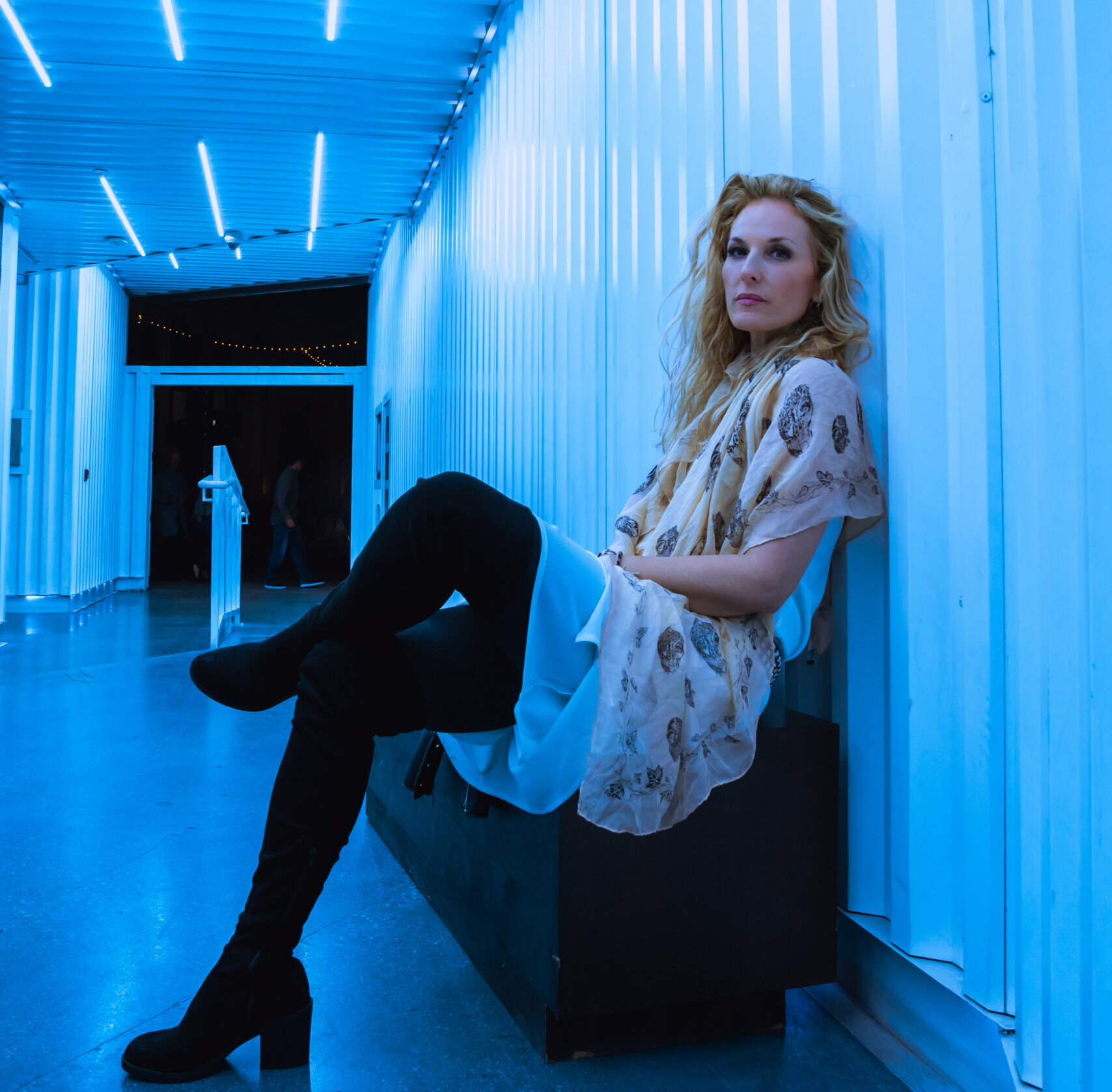 Actor Fabienne Grisel sitting on a bench in a blue alley.