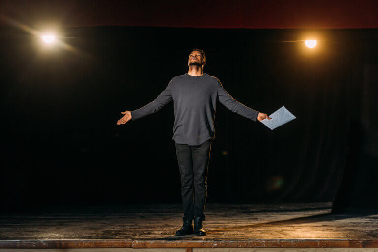 African American actor onstage, script in hand.