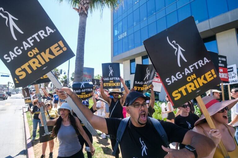 Striking SAG-AFTRA actors marching on the picket line, signs in hand.