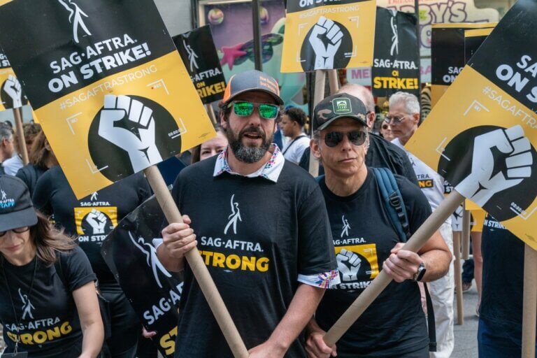 Adam Sandler and Ben Stiller on the SAG-AFTRA strike picket line with signs.
