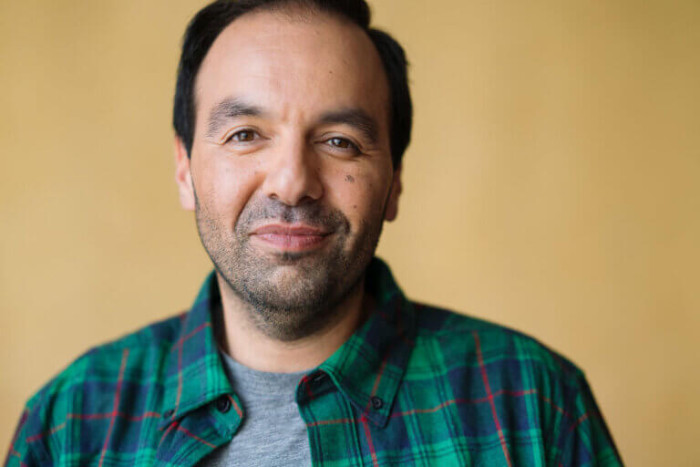 Actor Cesar Ramos in a flannel shirt smiling.