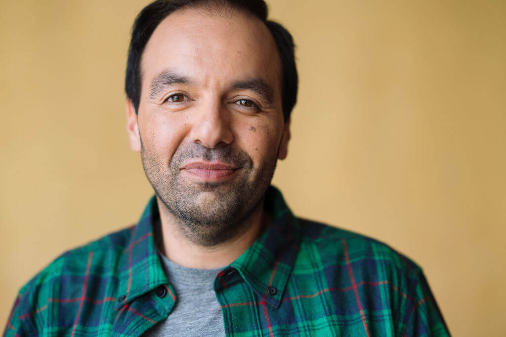 Actor Cesar Ramos in a flannel shirt smiling.