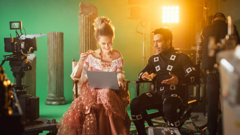 An actress in costume next to a motion capture actor in between scenes.
