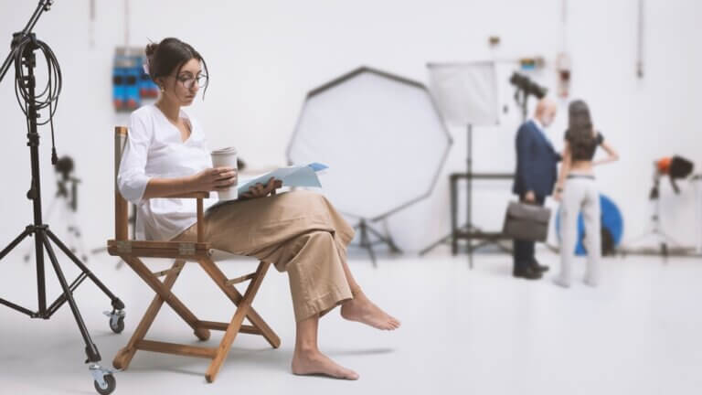 Actress reading lines on set, coffee in hand.