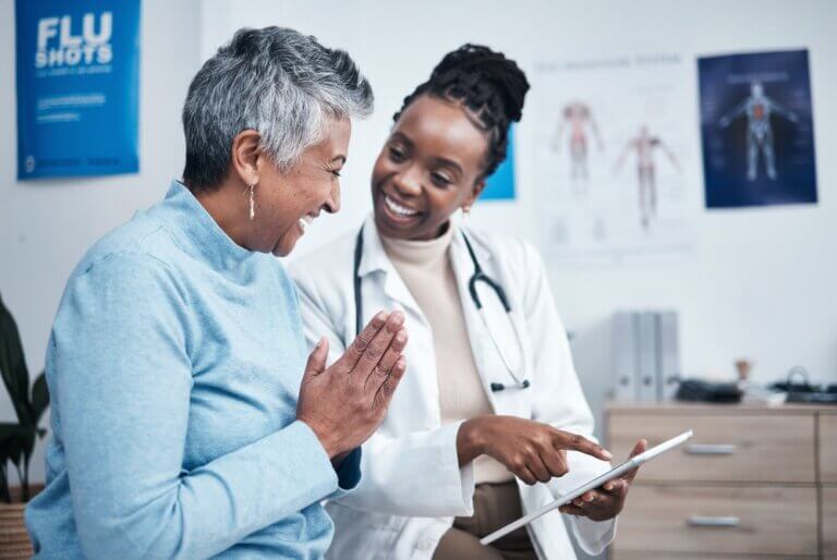 Elderly African American woman at an African American doctor's office happily thanking the female doctor for her service.