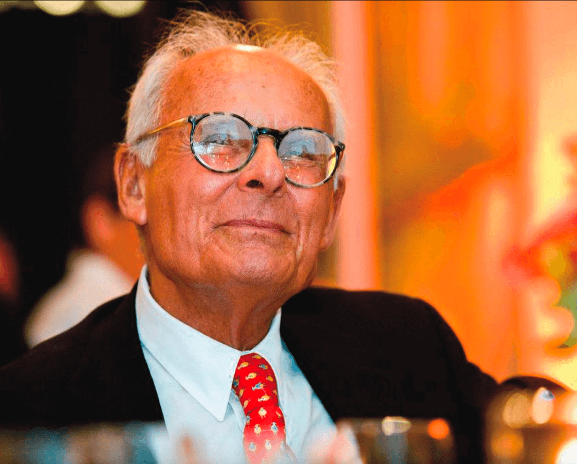 Hollywood legend Harry Abrams sitting down in a suit and smiling.