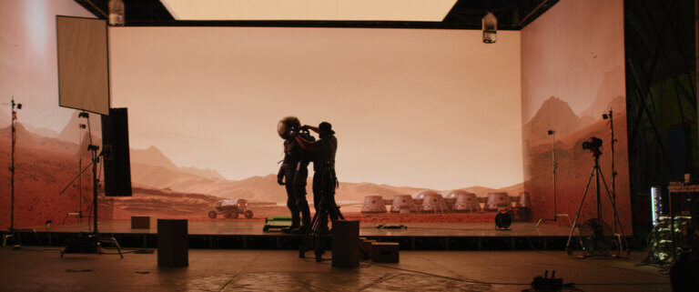 An actor in a spacesuit getting prepped to film on a soundstage.
