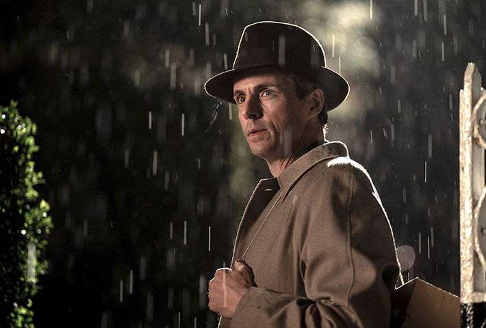 Actor Matthew Goode in a trench coat outside in the rain.