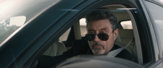 Ian McShane driving a car.