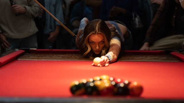 Lilli Simmons playing billiards inside.