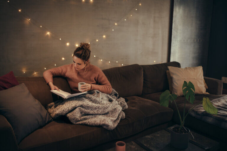 A woman reading a book on the couch.
